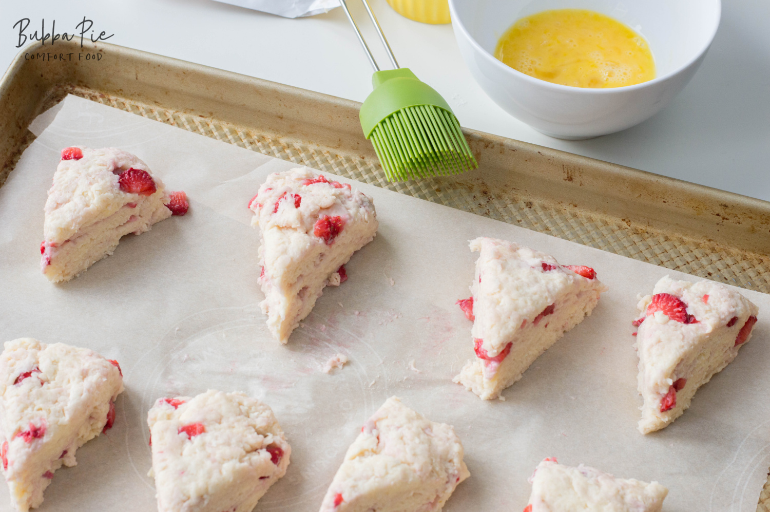 Fresh Strawberry Scones Recipe on a prepared baking sheet brushing the top with butter