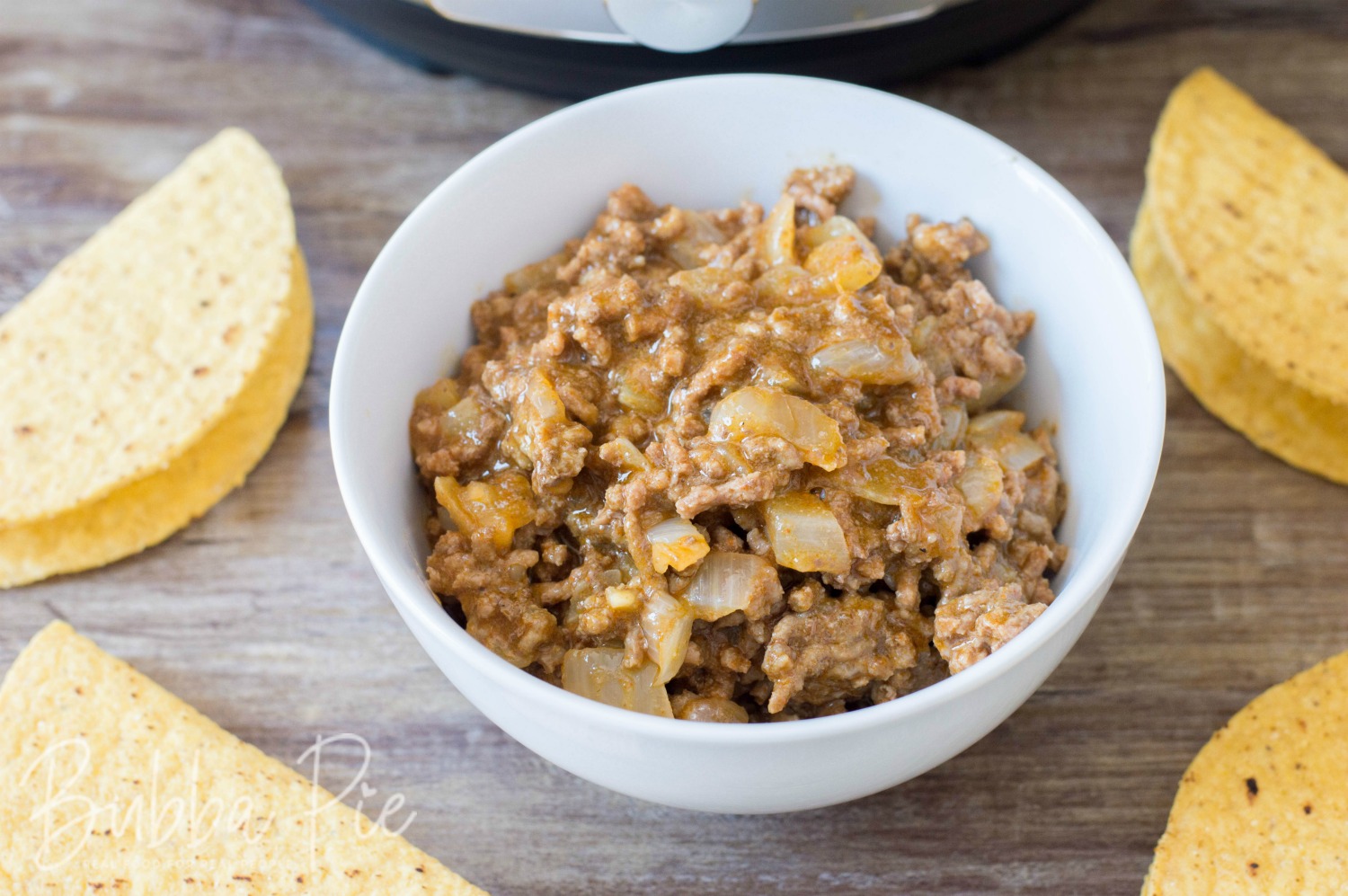 Instant Pot Taco Meat sitting next to a pressure cooker and taco shells