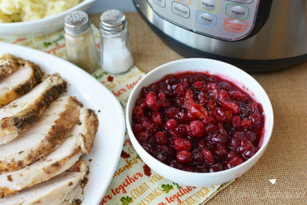 Instant pot Cranberry Sauce sitting next to a plate of turkey and a pressure cooker