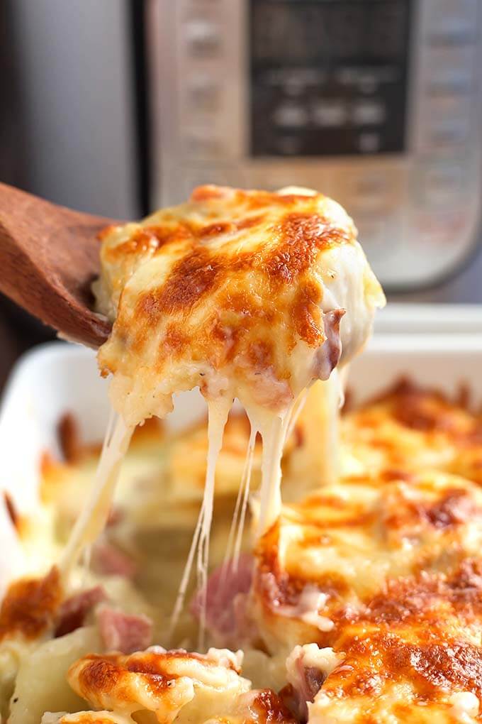 Pressure cooker Scalloped potatoes getting put onto a dish next to an Instant Pot