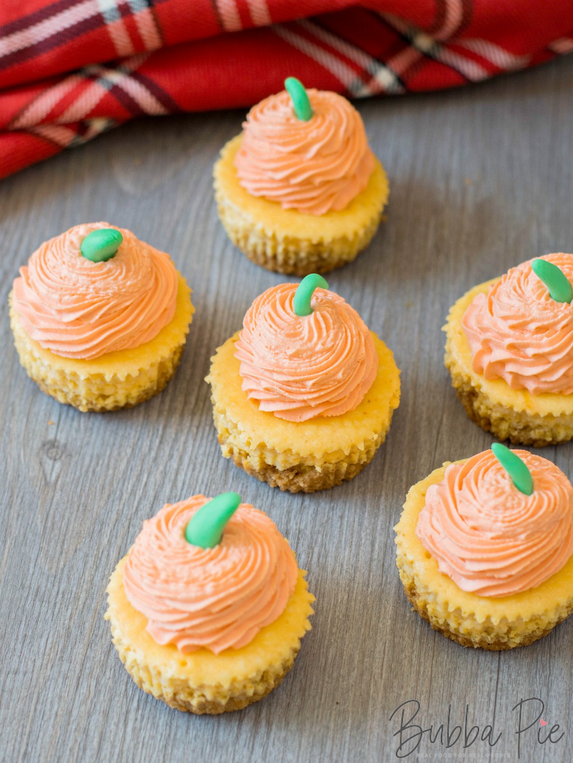 pumpkin cheesecake cupcakes with decorative fondant icing sitting on a table