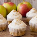 Apple Cinnamon Cupcakes with Buttercream Frosting sitting on a table with fresh apples makes a great thanksgiving dessert