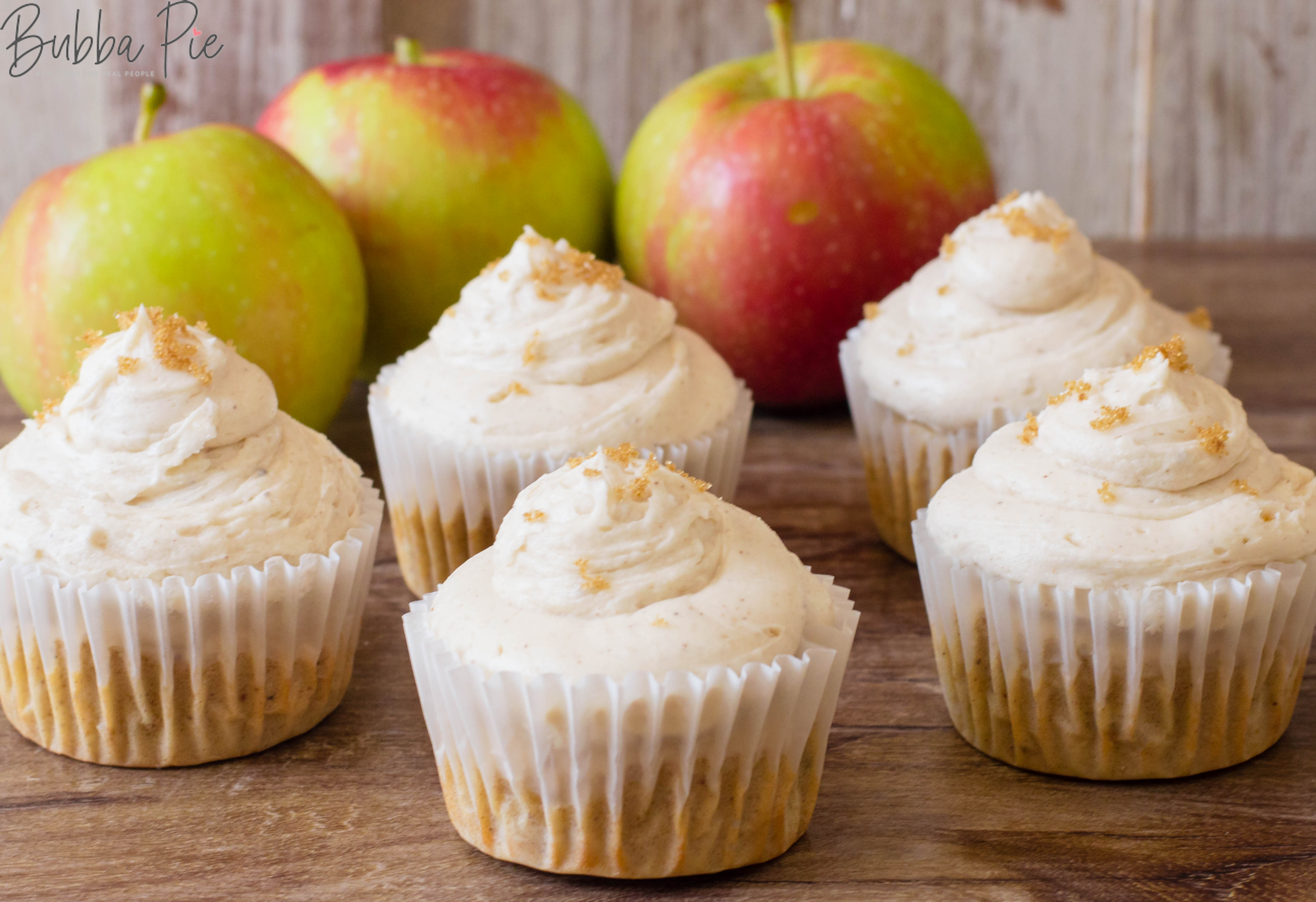 Apple Cinnamon Cupcakes with Buttercream Frosting sitting on a table with fresh apples makes a great thanksgiving dessert