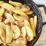 cracker barrel fried apples sitting in a skillet on a cuttingboard
