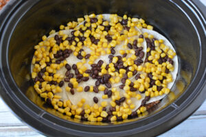 adding beans, corn, chilis and olives to mexican casserole