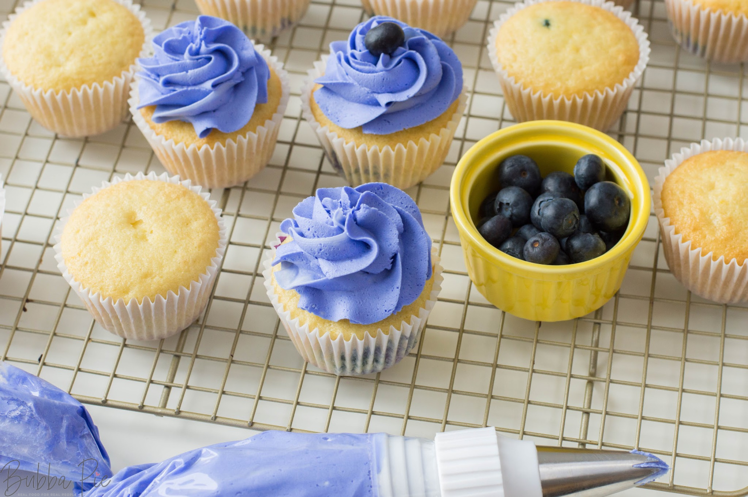 Lemon Blueberry Cupcakes getting topped with buttercream frosting