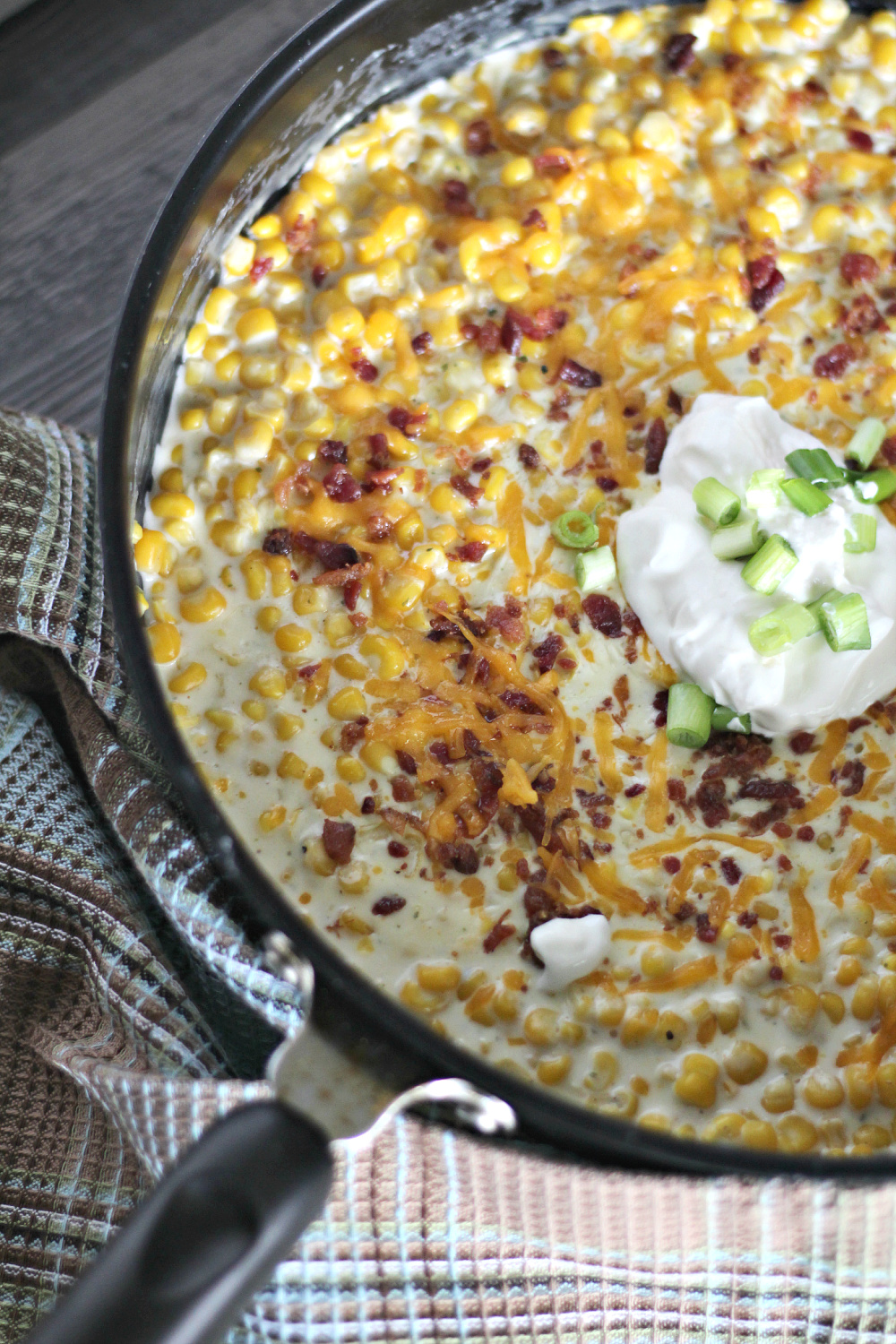 skillet cream cheese corn recipe is loaded with bacon, cheddar cheese, and green onions. 