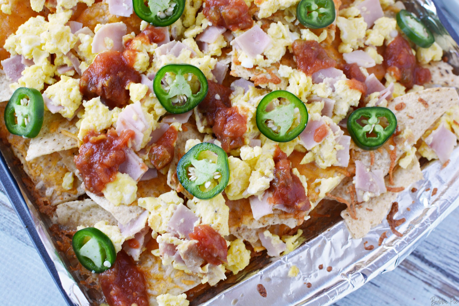 Breakfast Nachos loaded with ham, eggs, cheese and salsa