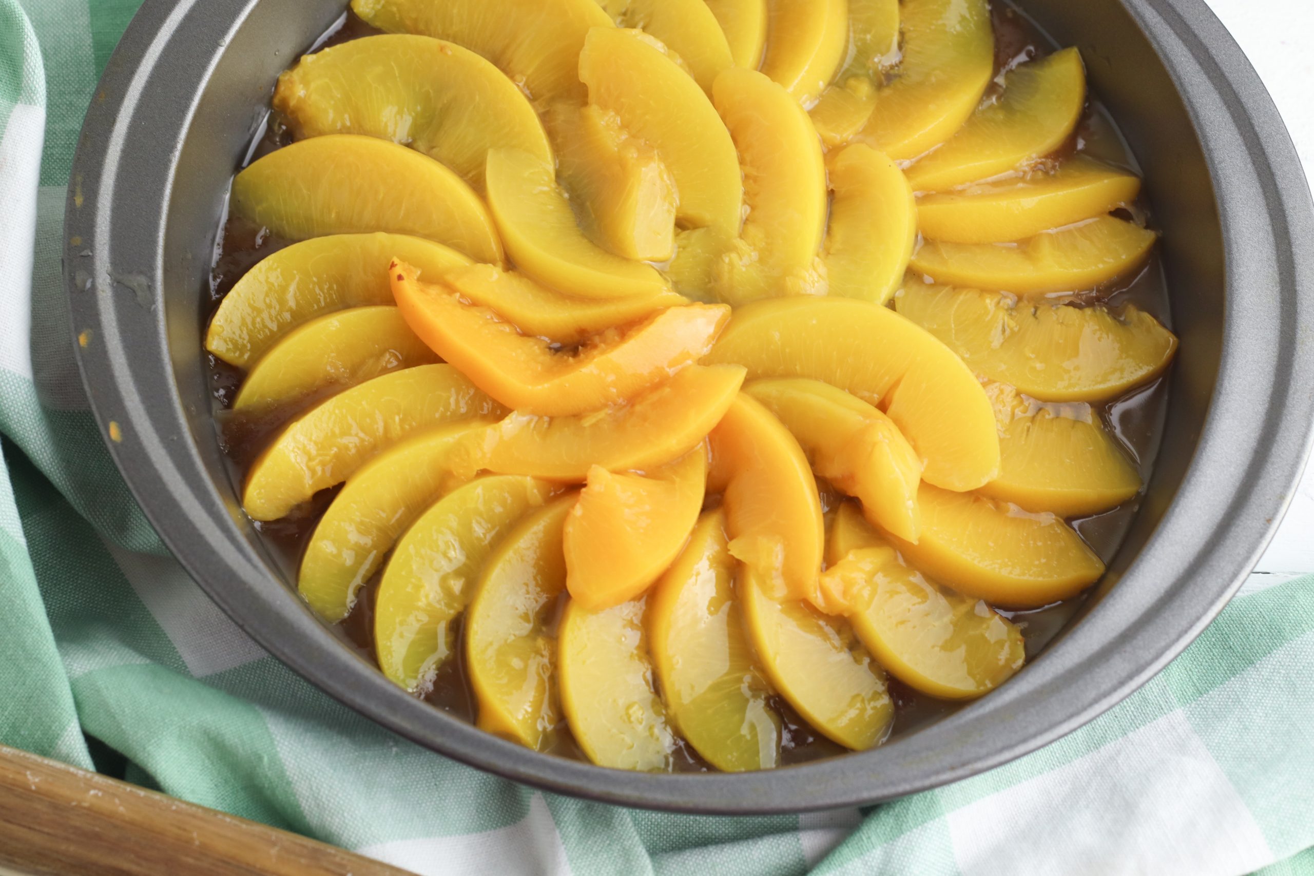 peach Upside Down Cake Instructions include putting the sliced peaches on a layer of cinnamon and brown sugar and butter. 