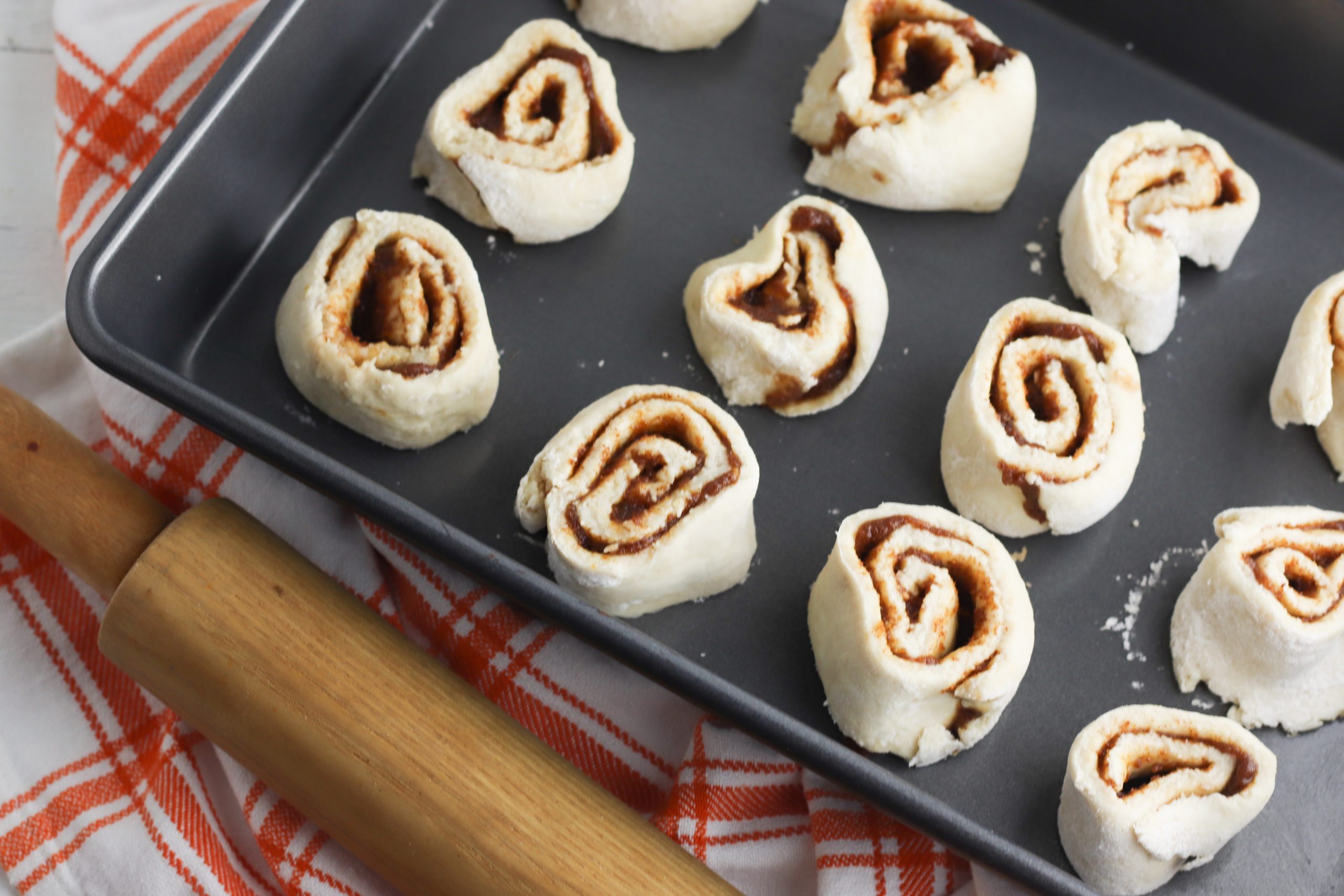 Pumpkin cinnamon rolls instructions include slicing the roll of dough and rolling them up on oven pan.