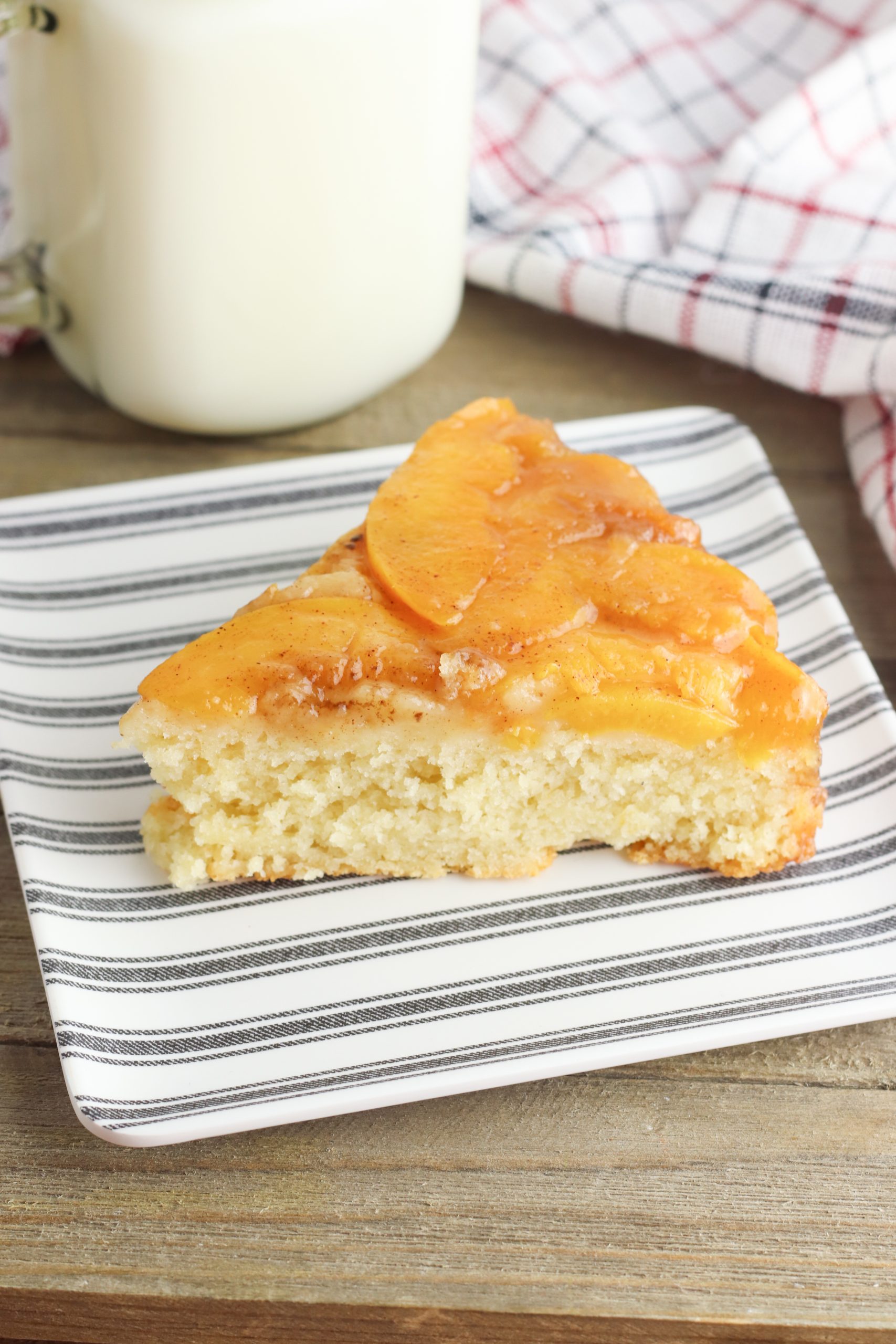 Upside Down Peach Cake Recipe being served for dessert on a plate with milk. 