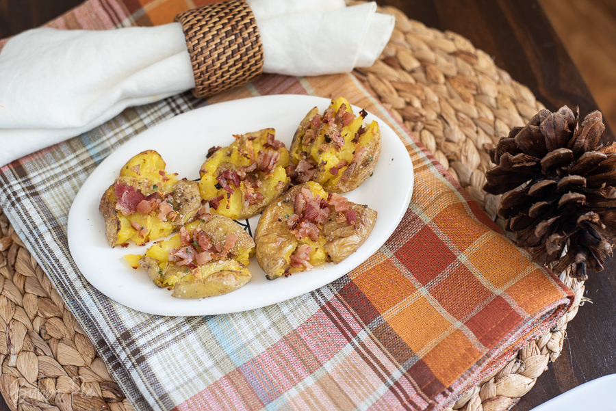 Smashed Potatoes being served on a table with Thanksgiving decorations.