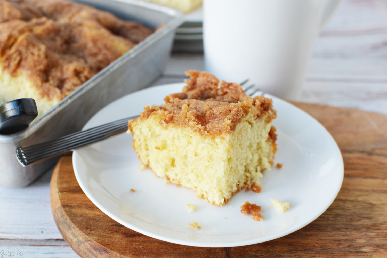 Bisquick Coffee Cake Recipe being served on a plate for breakfast with a cup of coffee. 