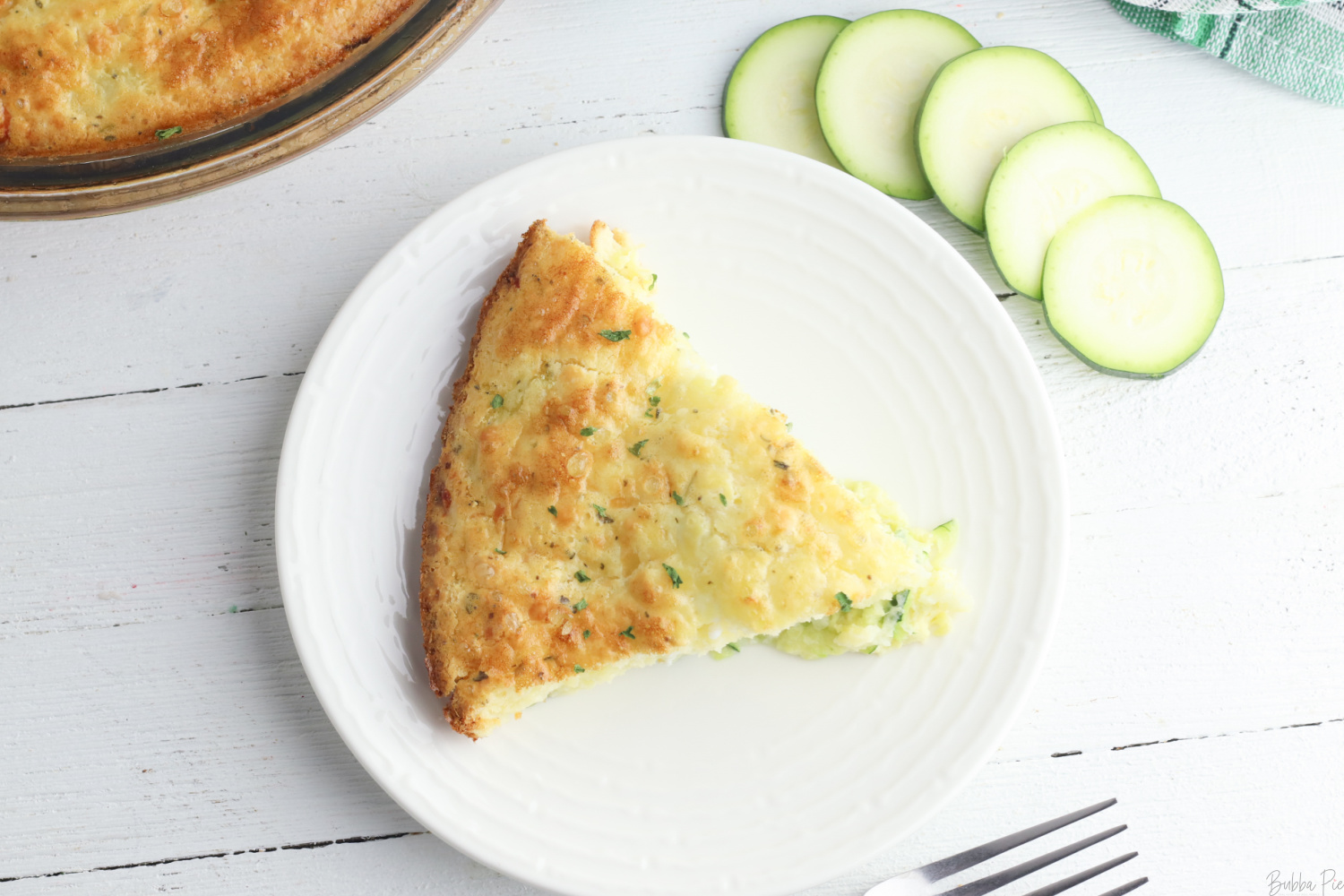 Bisquick Zucchini Quiche being served on a white plate. 