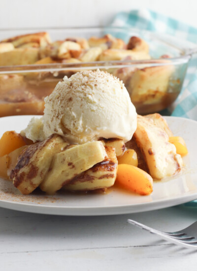 Cinnamon Roll Peach Cobbler Recipe being served on a white plate.