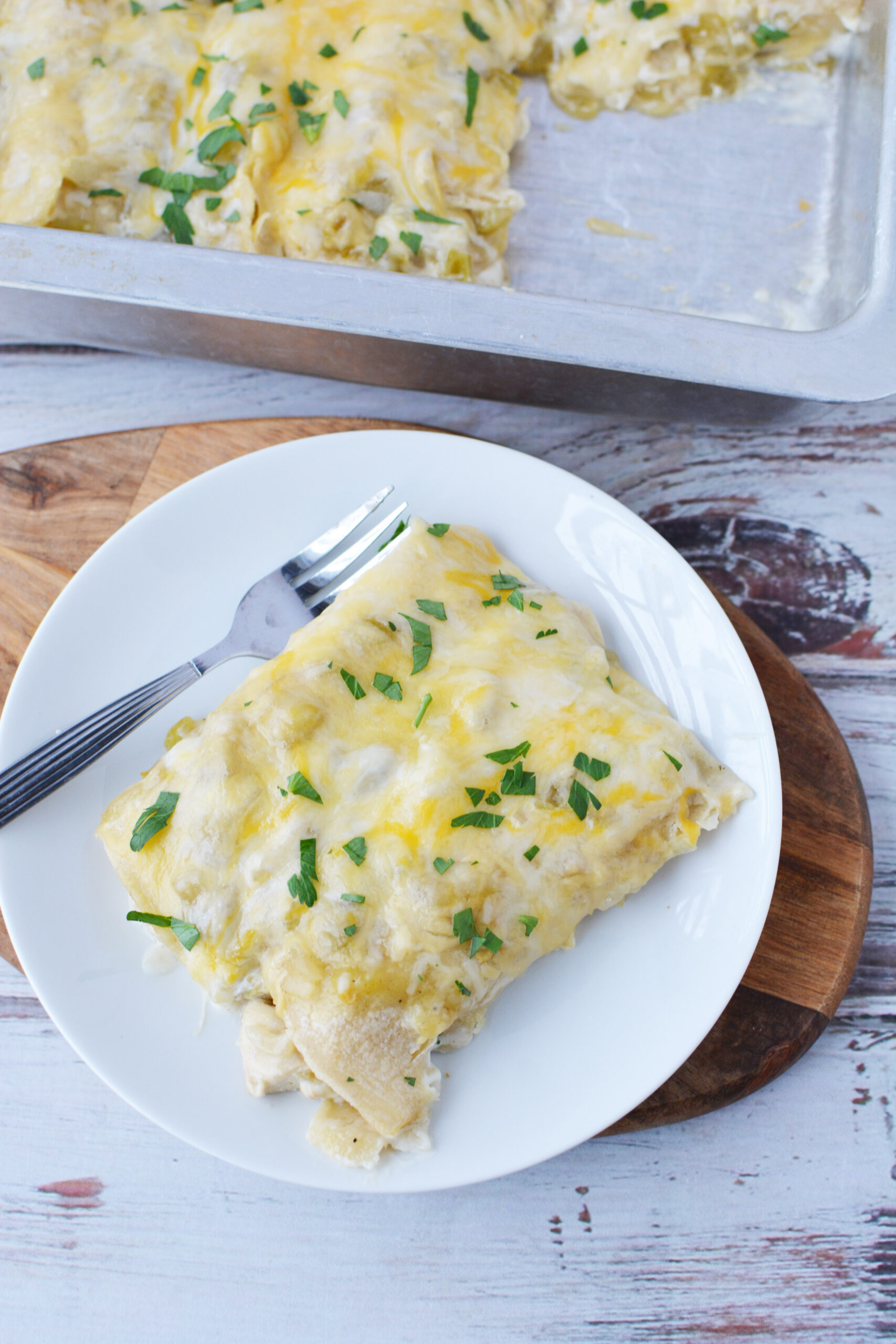 Creamy Chicken Enchiladas Suiza sitting next to a casserole pan out of the oven.
