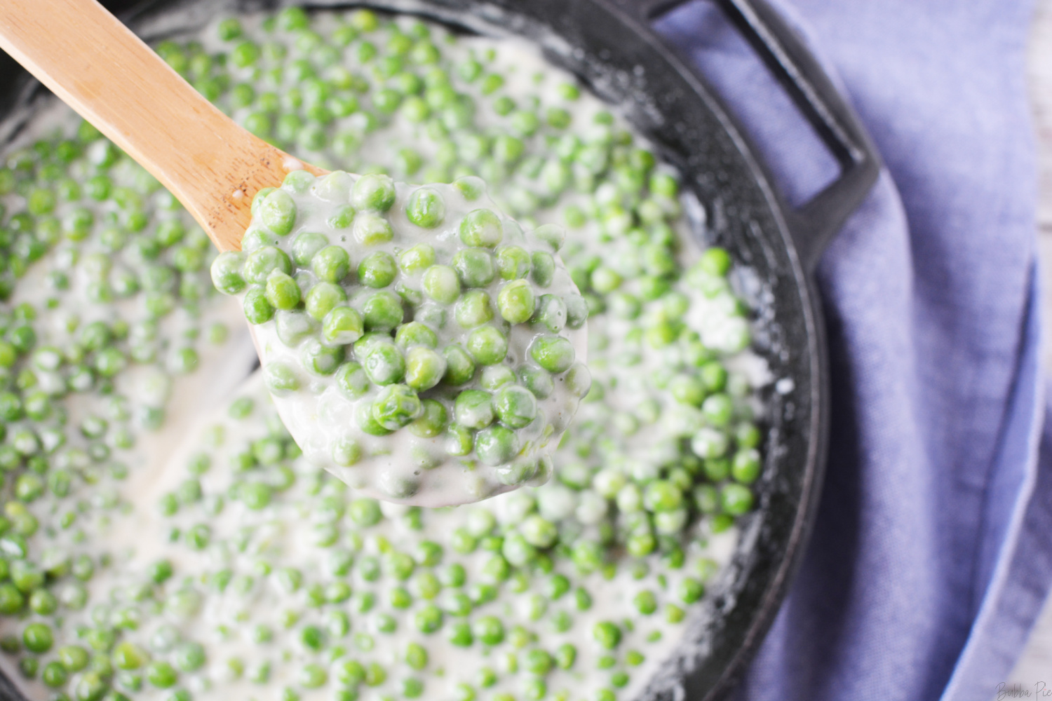 Classic Creamed Peas being served from stovetop skillet
