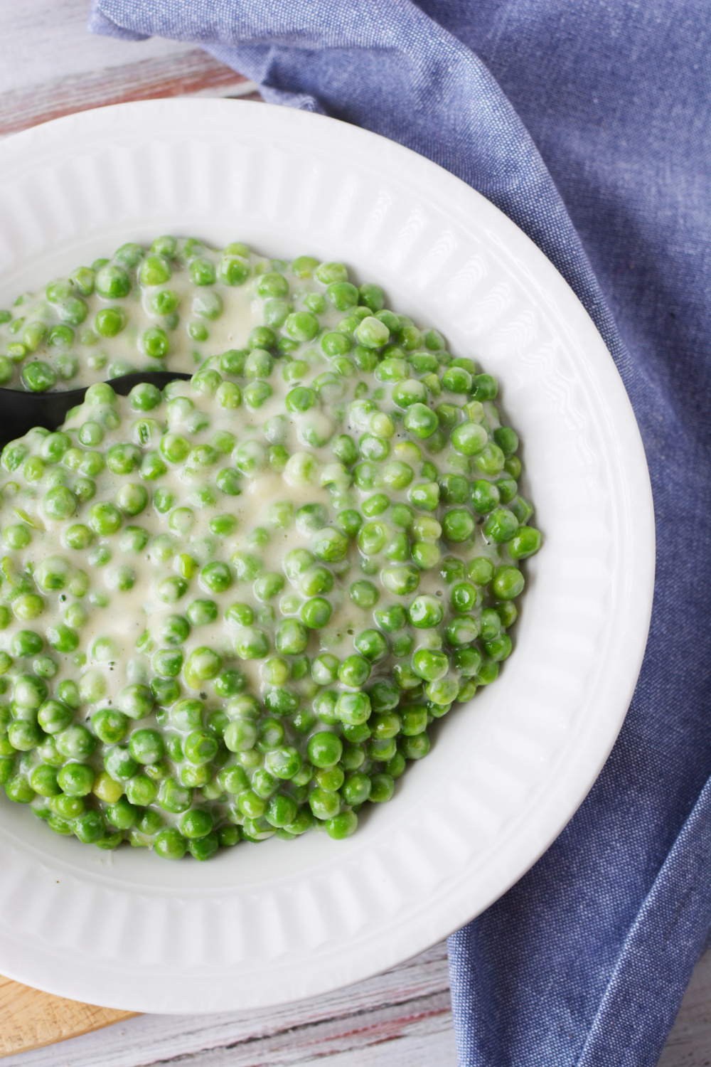 Creamed Peas Recipe being served as a side dish in a white bowl.