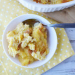 Pineapple Souffle Casserole being served on a white plate with a spoon.