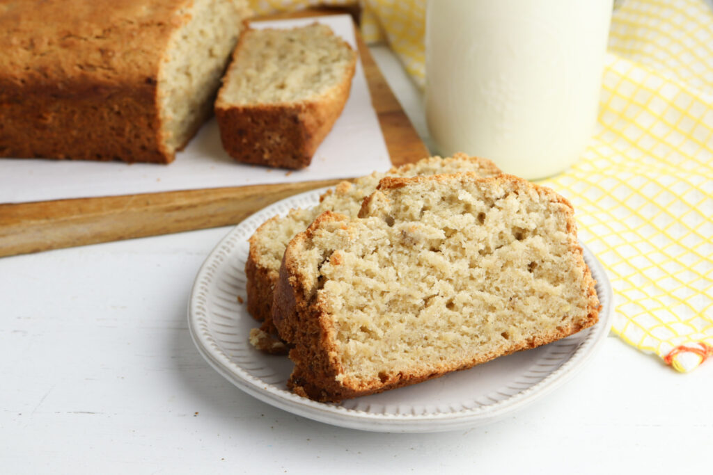 banana bread on a white plate with a glass of milk.