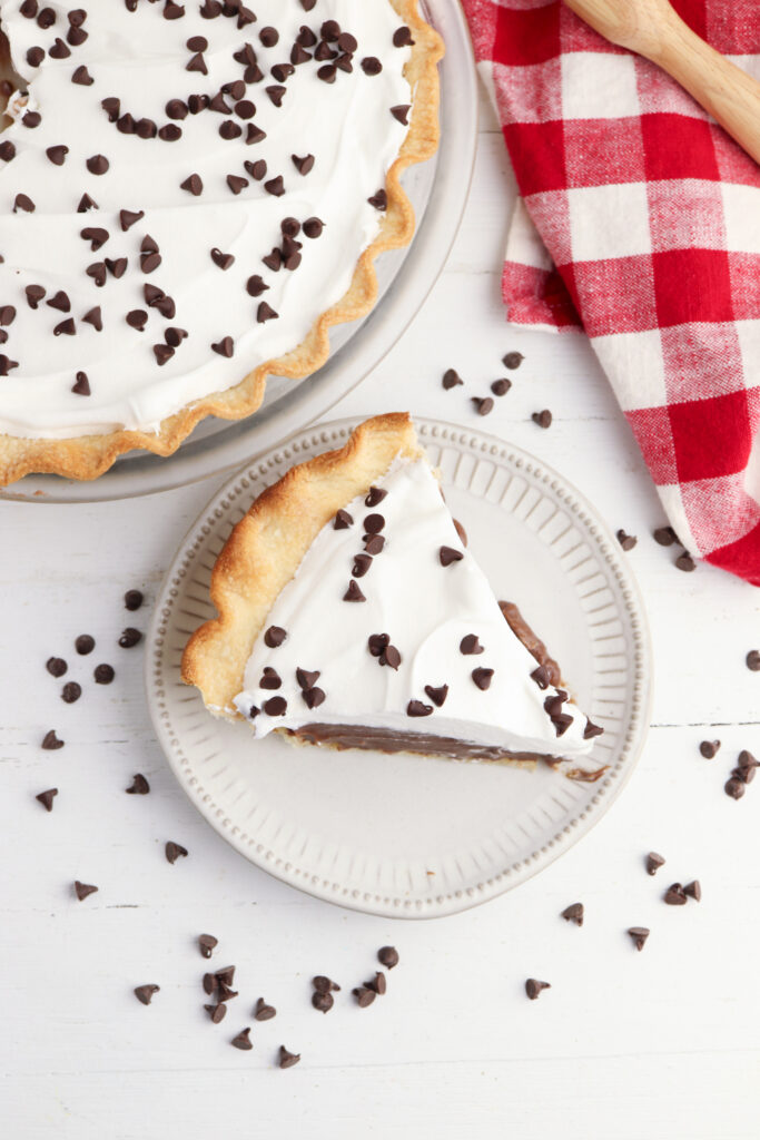 Chocolate Cream Pie laying on a white plate with chocolate chips. 