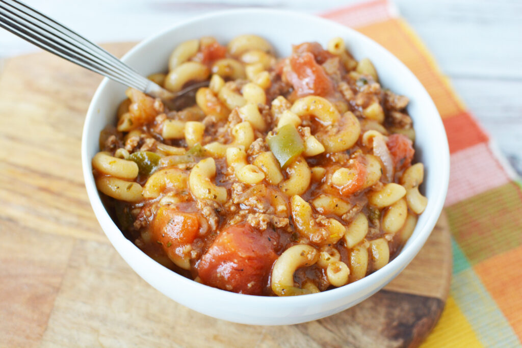 Easy Goulash Recipe with a spoon in a white bowl. 