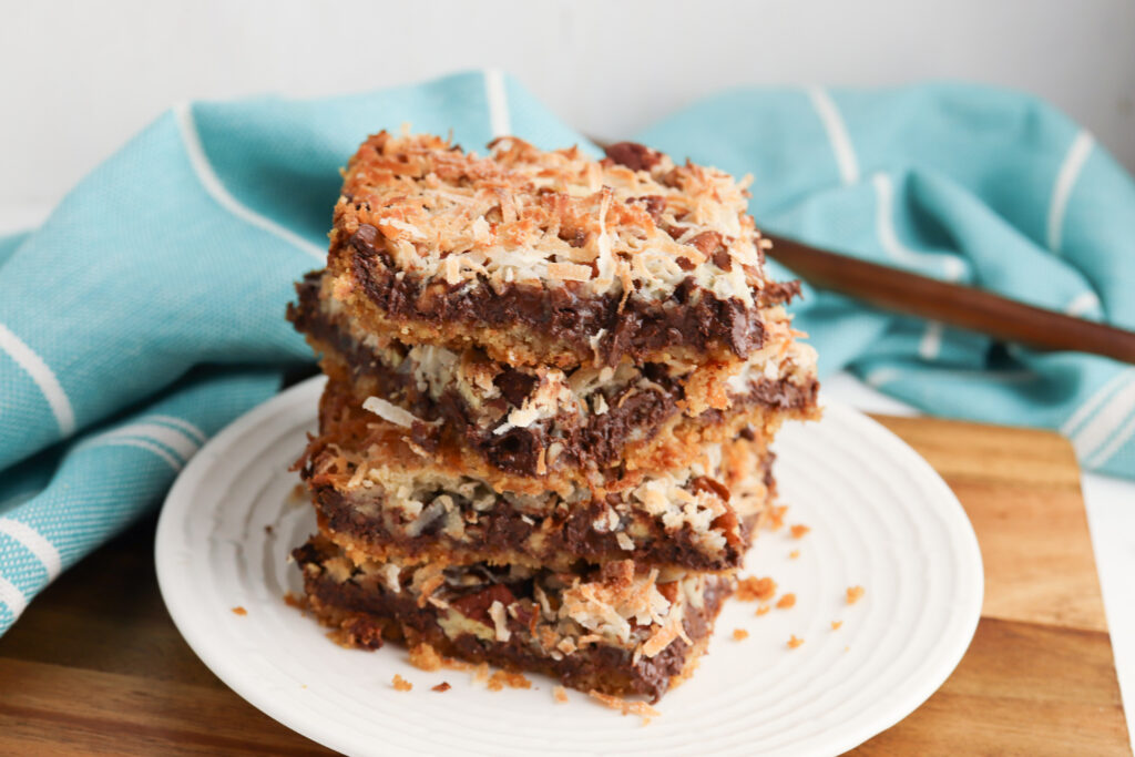 Hello Dolly Bars stacked on a white plate.