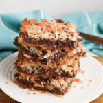 Hello Dolly Bars stacked on a white plate.