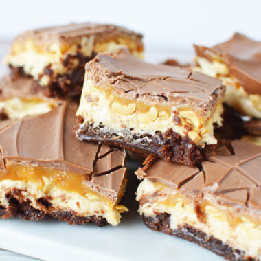 Snickers Brownies stacked on a plate.