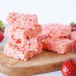 Strawberry Rice Krispies Treats laying on a platter with strawberries.