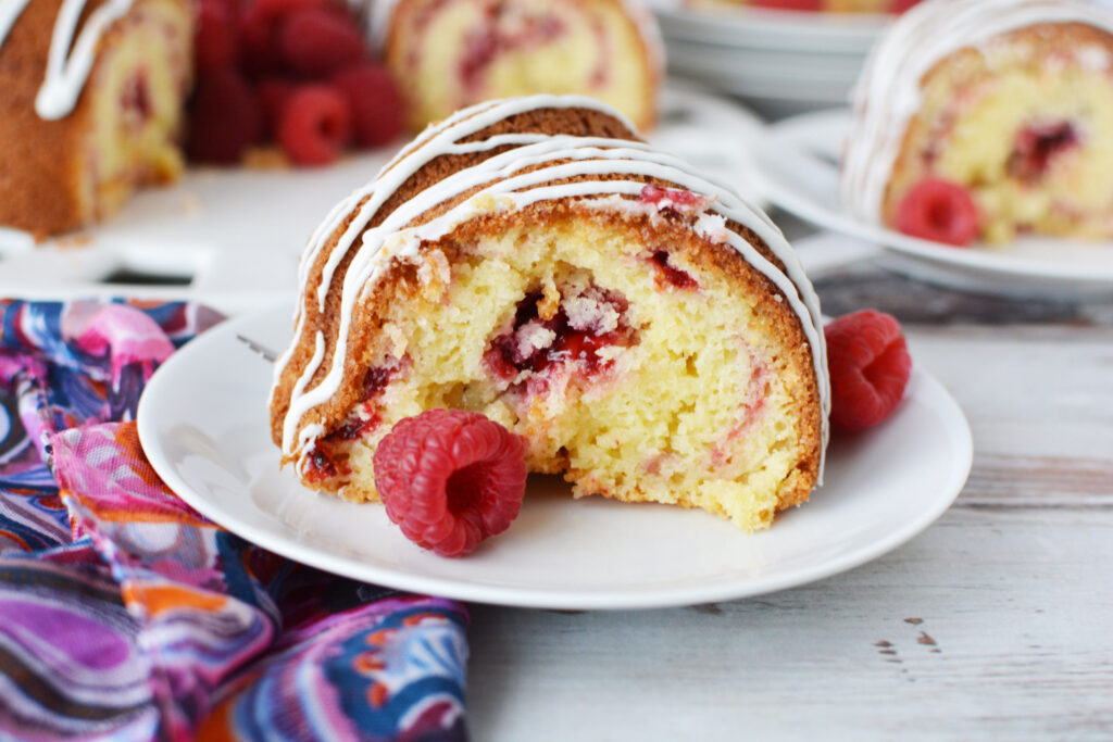 White Chocolate Raspberry Bundt Cake being served on a white plate.