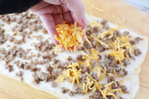 sprinkle dough with sausage and cheese