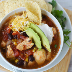 chicken tortilla soup topped with avocado, cheese and tortilla chips.