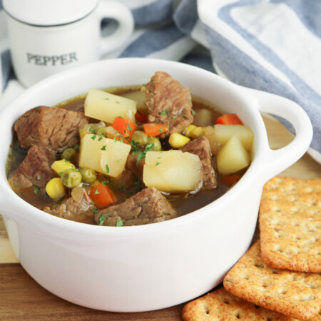 Vegetable beef soup sitting on a table with some crackers