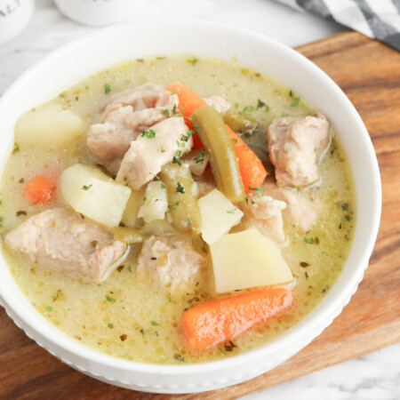 pork stew served in a white bowl on a wooden board