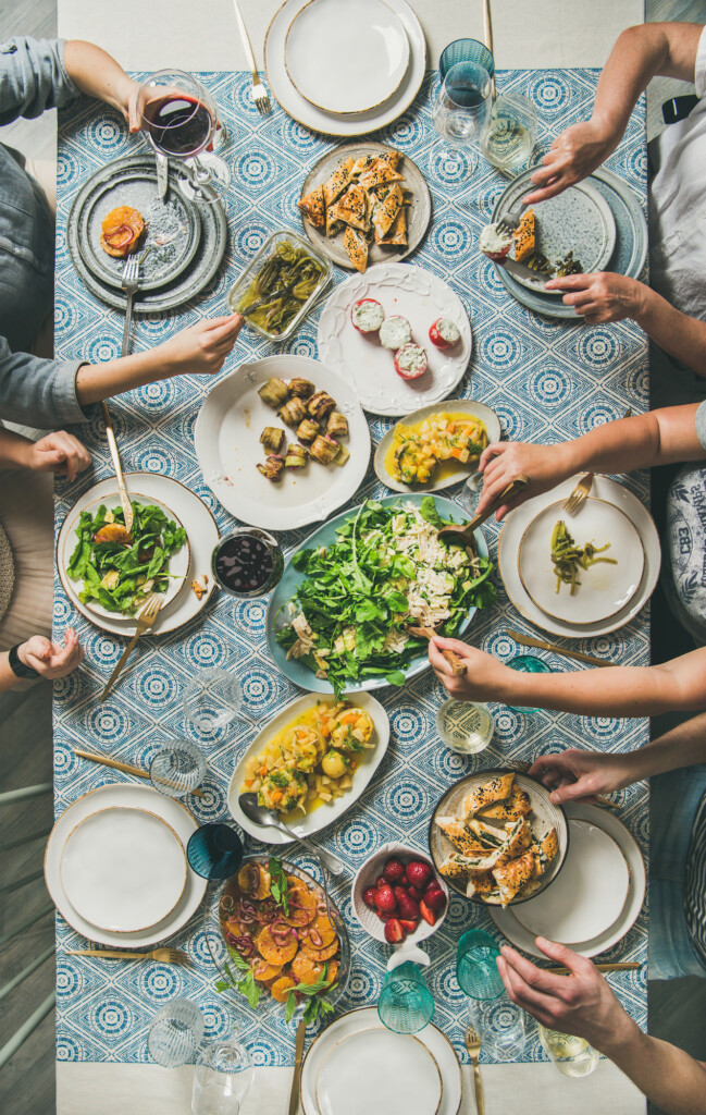 Mediterranean style dinner and human hands holding drinks and food