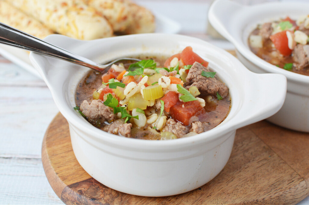 beef barley soup in a white bowl with a spoon